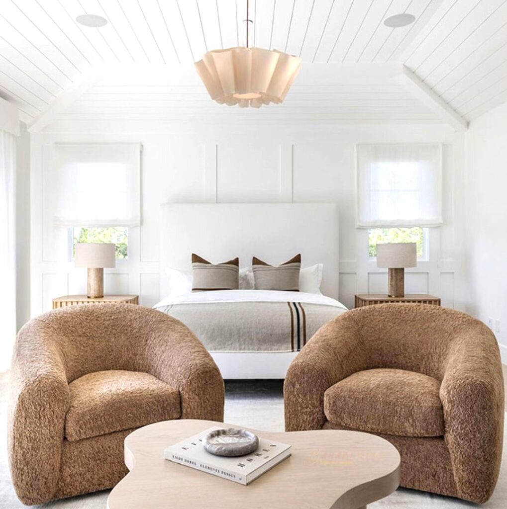 White master bedroom with brown chairs beside
